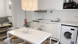 A modern kitchen with white cabinetry, a built-in microwave, and a washing machine.