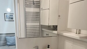 A modern bathroom with a white sink, a mirror, and a towel rack.