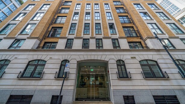 Un immeuble à étages doté d’une façade symétrique, de grandes fenêtres et d’une entrée centrale avec des portes en verre.