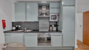 Une cuisine compacte équipée d’un four à micro-ondes, d’un four traditionnel et d’un évier.