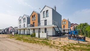 Ein modernes, mehrgeschossiges Wohngebäude mit flachem Dach, großen Fenstern und einem Balkon.