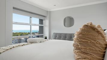 A modern bedroom with a large bed, a view of the city, and a cityscape through the window.