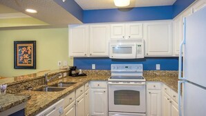 A kitchen with white cabinets, a granite countertop, a microwave, an oven, and a sink. - Oceanfront 2 BR Condo Tons of Amenities Low Floor! (Myrtle Beach)