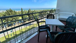Un balcon avec vue sur la mer, une table et des chaises.