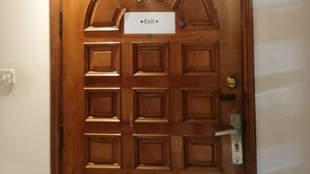 A wooden door with a sign that reads "Exit".