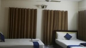 A hotel room with two single beds, a ceiling fan, and brown curtains.