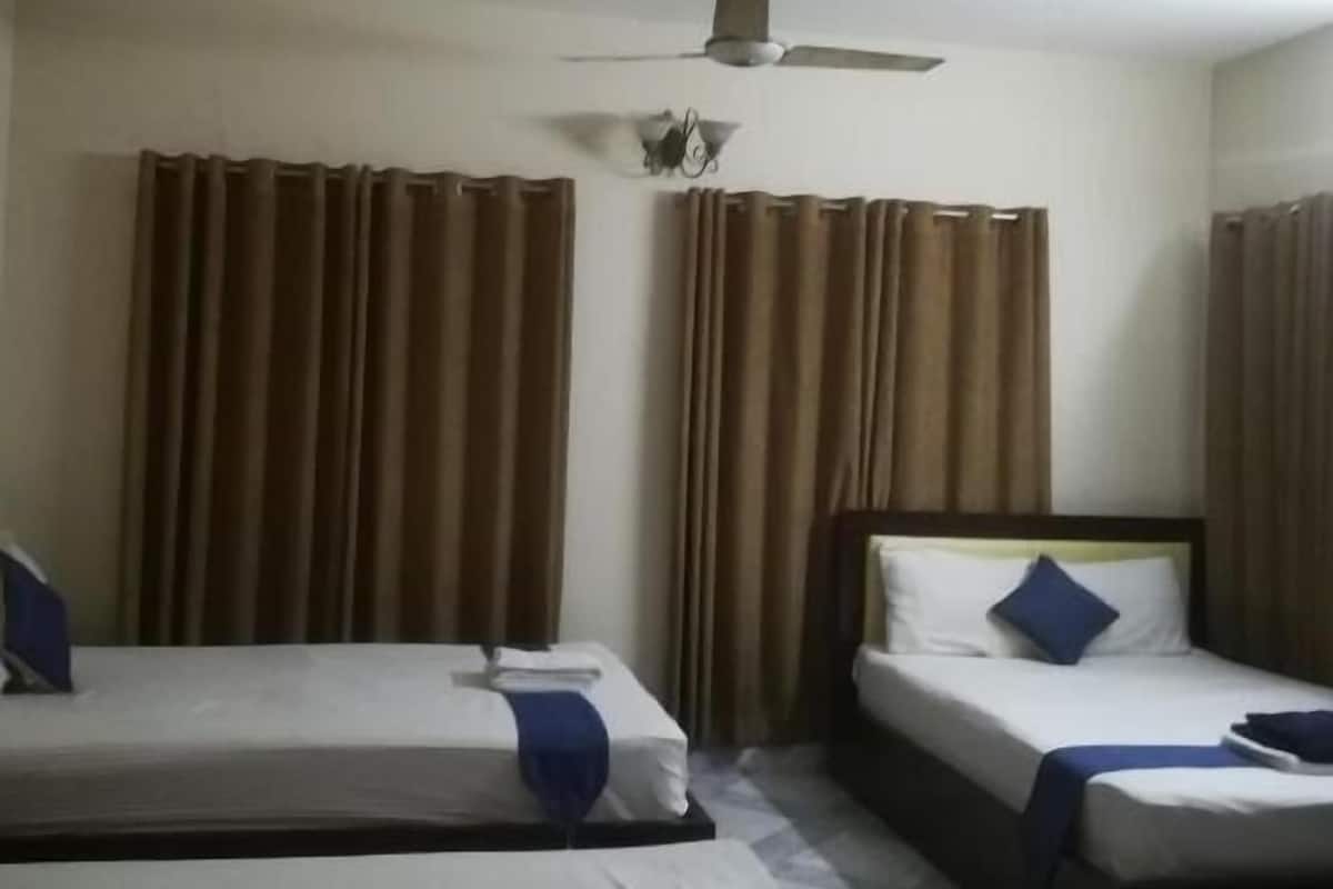 A hotel room with two single beds, a ceiling fan, and brown curtains.