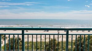 A beach view from a balcony with a railing, palm trees, and the ocean. - Oceanfront 3 BR Condo Tons of Amenities 3rd Flr (Myrtle Beach)