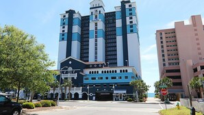 A multi-story hotel with a prominent 'Paradise' sign, a gated entrance, and a stop sign at the corner. - Oceanfront 3 BR Condo Amazing Views 5th floor (Myrtle Beach)