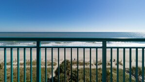 A beach view from a balcony with a railing, sandy beach, and ocean. - Oceanfront 3 BR Condo Amazing Views 5th floor (Myrtle Beach)