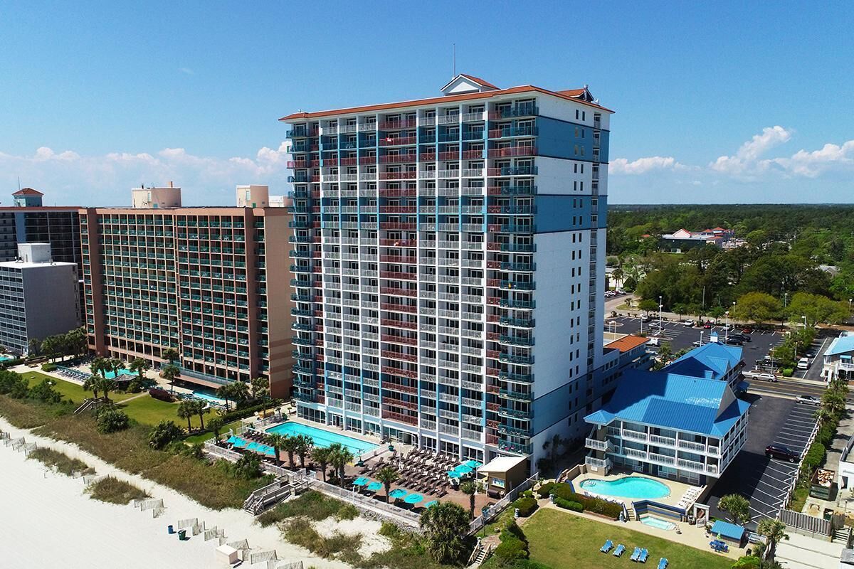 Un hôtel de grande hauteur doté de nombreux balcons, d’un espace piscine et offrant une vue sur la plage.