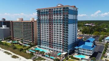 Un hôtel de grande hauteur doté de nombreux balcons, d’un espace piscine et offrant une vue sur la plage.
