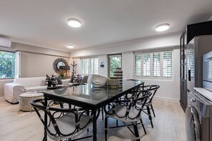 Una cucina moderna con zona pranzo, che include un tavolo con piano in vetro, sedie in vimini nero e forno a incasso.