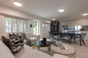 Uma sala de estar moderna com sofá, mesa de centro e área de jantar com cadeiras.