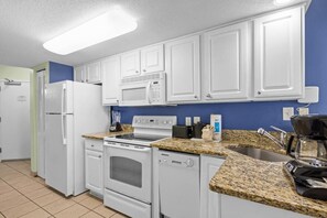 A kitchen with white cabinets, a microwave, a stove, a dishwasher, and granite countertops. - Unwind 1BR Oceanfront Queen Deluxe Condo 4TH Floor (Myrtle Beach)