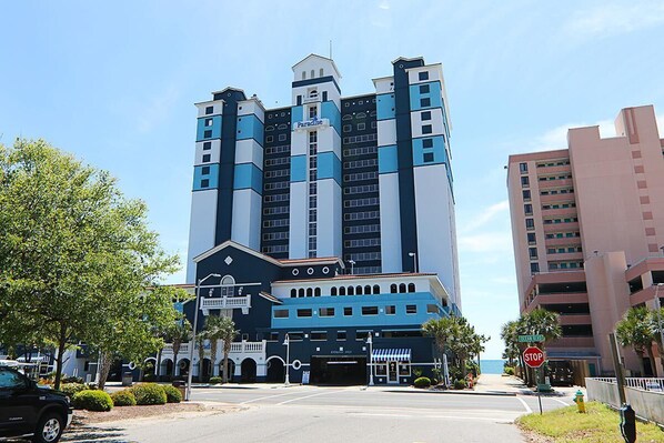 A multi-story hotel with a prominent 'Paradise' sign, a gated entrance, and a stop sign at the corner.