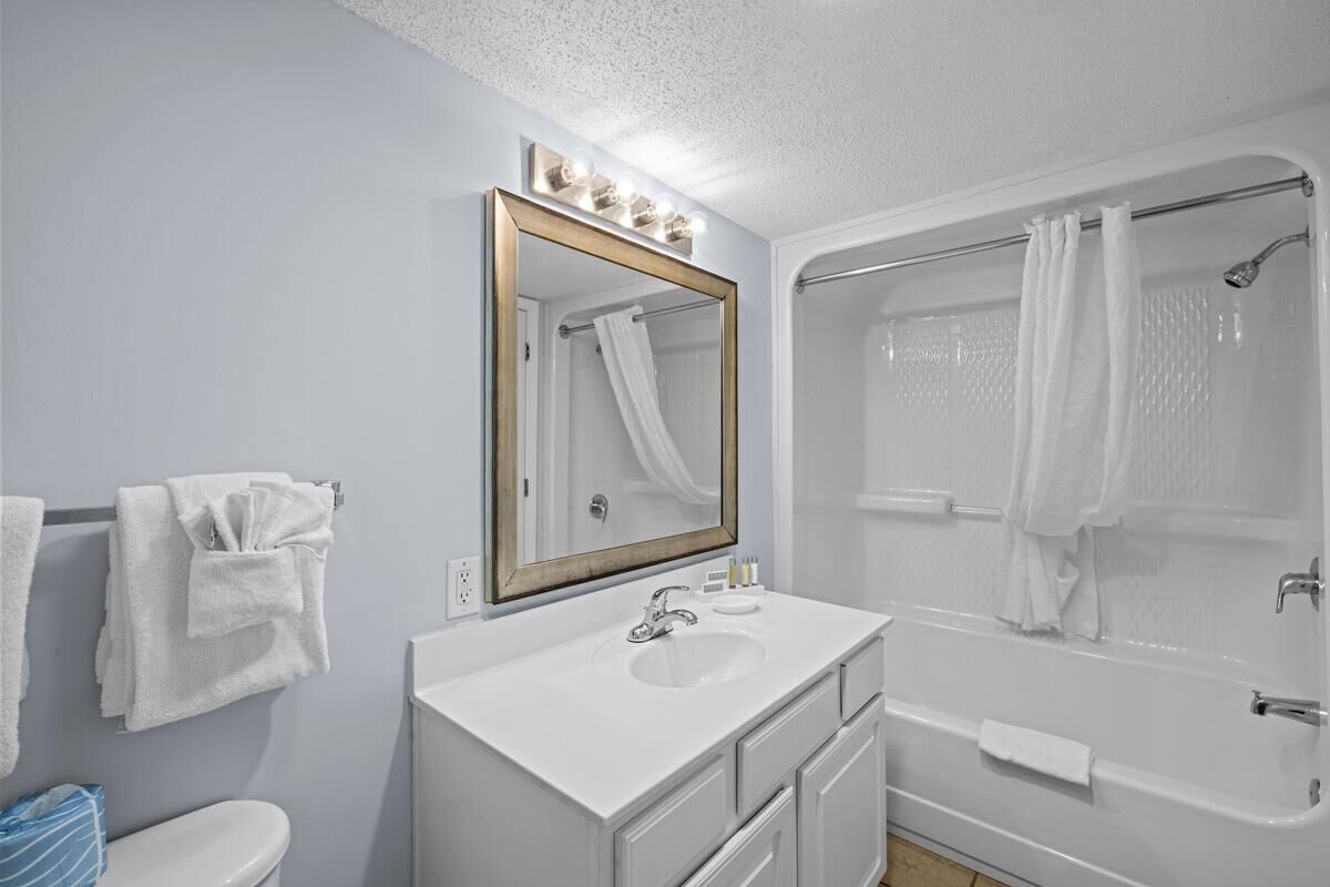 A bathroom with a white sink, a large mirror, a bathtub, and a shower.