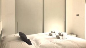 Ein modernes Hotelzimmer mit einem Bett, einem Kissen und einem kleinen Nachttisch mit einer Lampe.