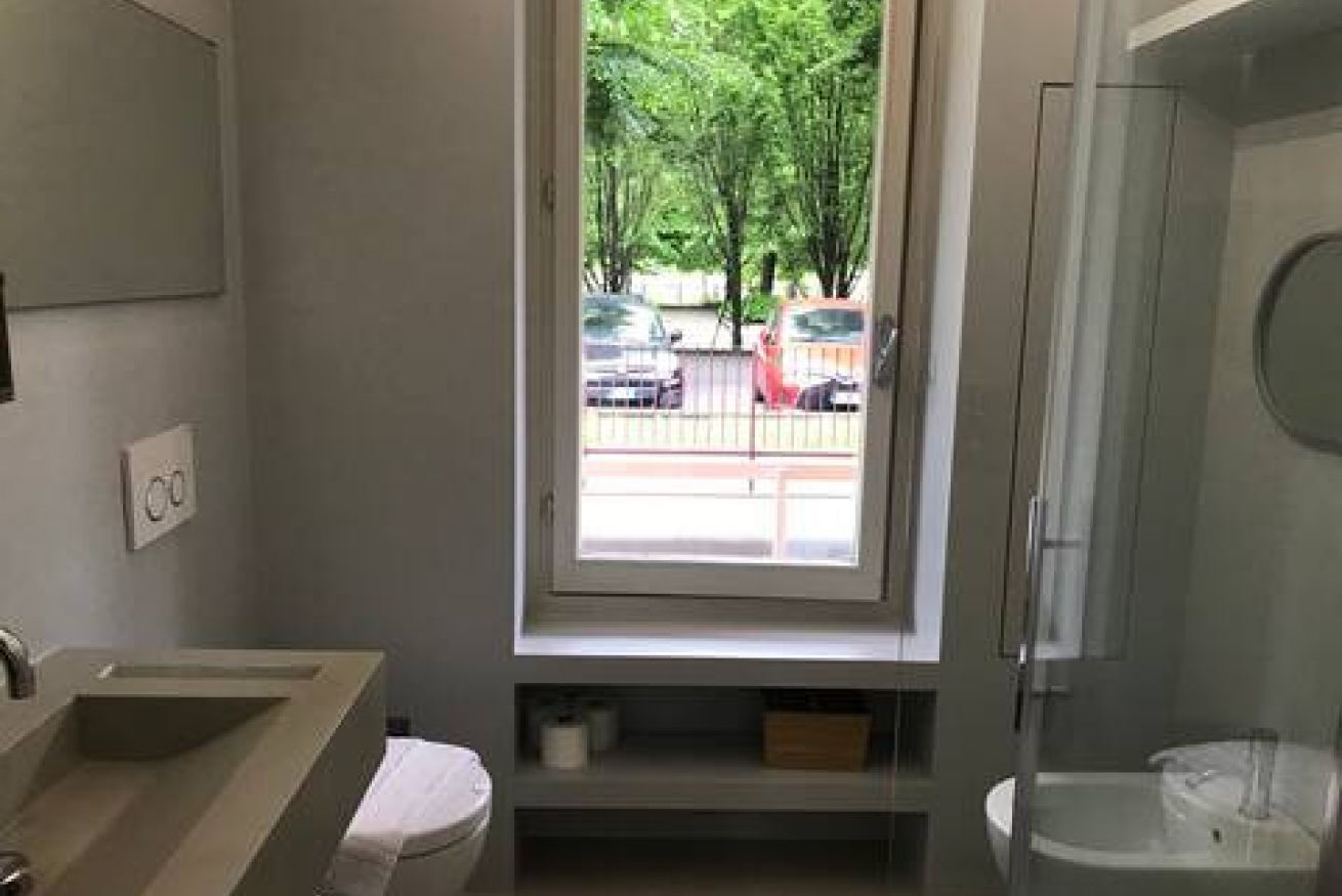 Un baño con ventana, lavabo, inodoro y ducha.