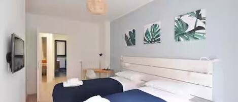 A bedroom with a bed, bedside table, and a wall-mounted TV.