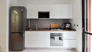 A compact kitchen with a built-in oven, a microwave, and a coffee machine. - GuestHost - CASA CRI&ELI: trilo x5 con terrazzo (Milan)