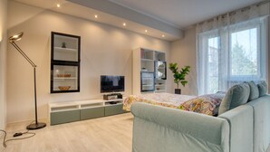 Une chambre moderne avec un lit, un téléviseur intégré, des meubles de rangement et une grande fenêtre.