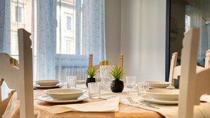 Une table à manger dressée pour quatre personnes, avec des assiettes, des verres et des couverts, ainsi que deux petites plantes en pot.