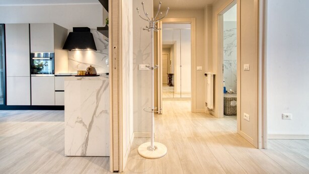 Une cuisine moderne dotée de plans de travail en marbre, d’un îlot central et d’un luminaire suspendu noir.