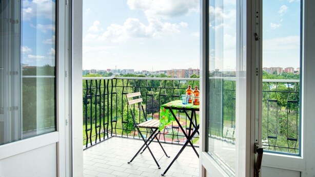 A balcony with a table and chairs, a view of a cityscape, and a clear sky. - GuestHost - ParkView House! (Milan)