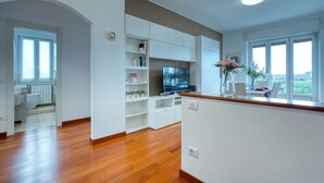 A modern living room with a flat-screen TV, built-in shelves, and a dining area with a table and chairs. - GuestHost - ParkView House! (Milan)