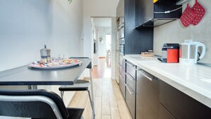 A modern kitchen with stainless steel appliances, a dining table with chairs, and a visible hallway leading to another room. - GuestHost - ParkView House! (Milan)