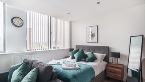 Un dormitorio moderno con cama, mesita de noche, espejo y ventana con persianas.