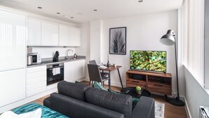 Un apartamento moderno con kitchenette, comedor, sala de estar con sofá y televisor.
