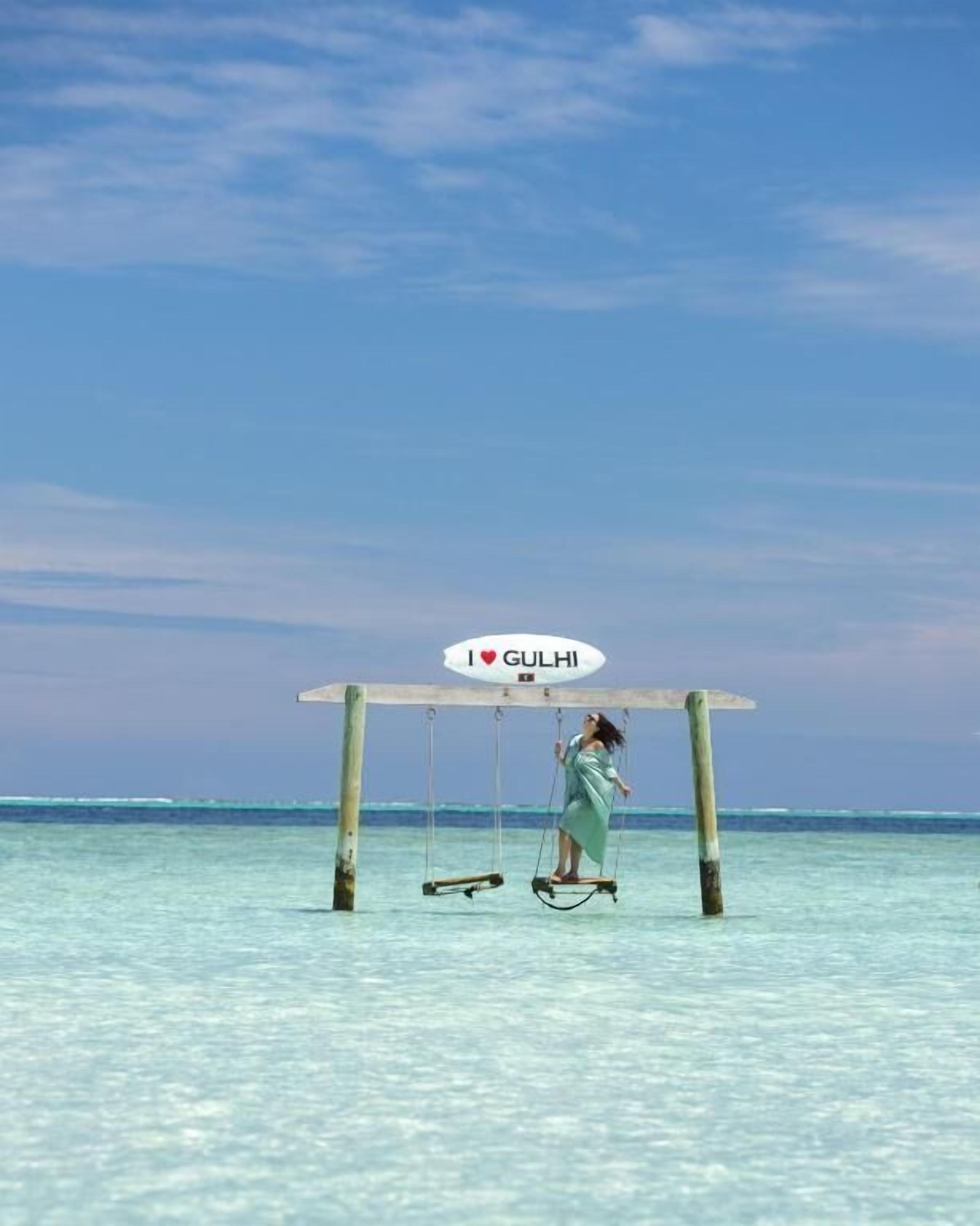A swing set with a sign that reads "I love GULAHI" in a clear blue sky.