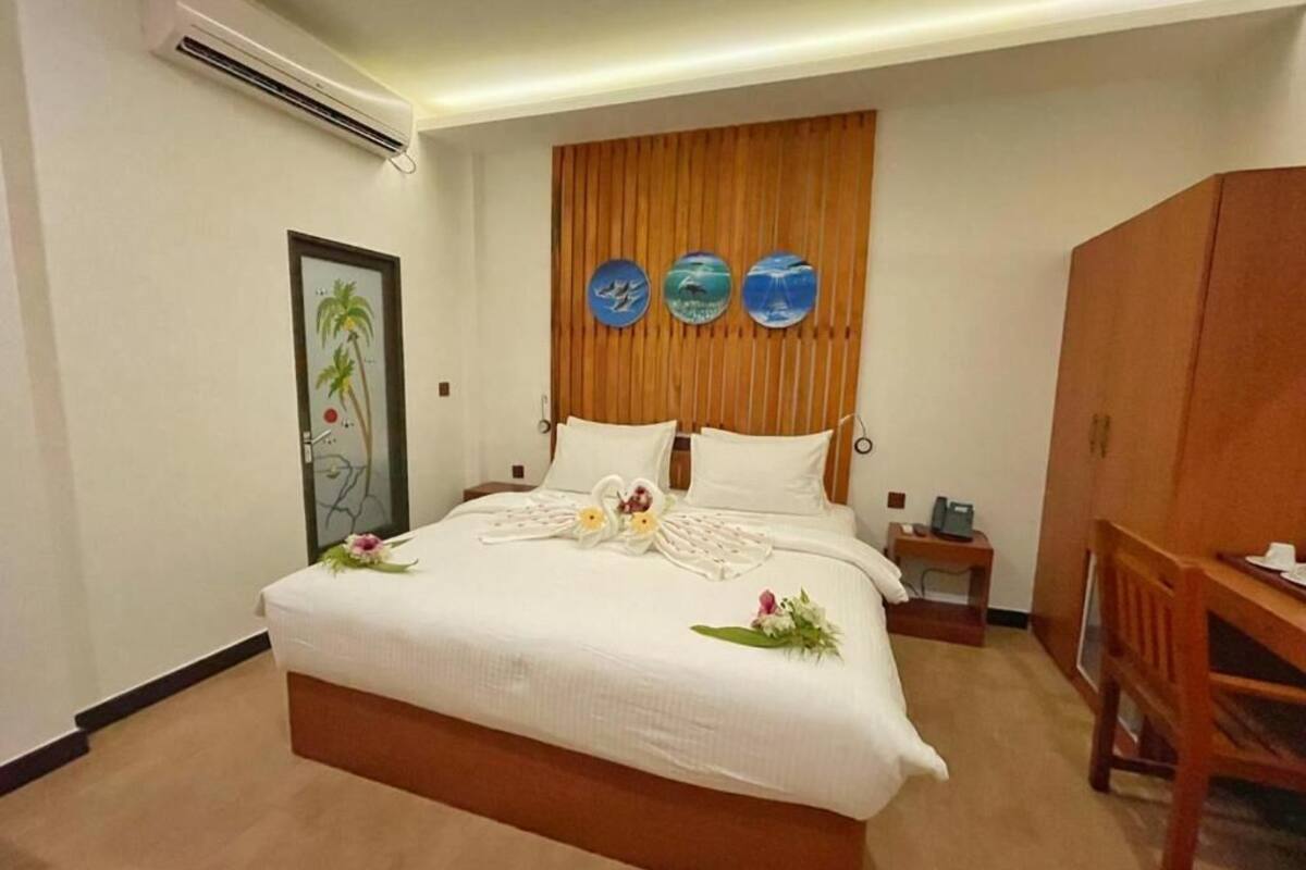 A neatly made bed with white linens, a wooden headboard, and decorative wall art.