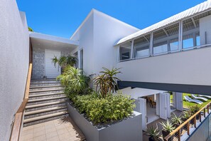 Ein modernes Gebäude mit einer Treppe, die zu einem Balkon mit Pflanzen und Sitzgelegenheiten führt.