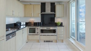 Een moderne keuken met roestvrijstalen apparatuur, houten kastjes en een groot raam met uitzicht.