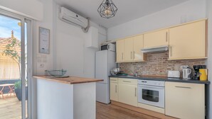 A compact kitchen with a built-in oven, a refrigerator, and a coffee maker. - Appartement 3 Pièces Avec Terrasse au Calme Hyper Centre Arcachon - Mer à 50 m (Arcachon)