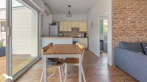 A modern kitchen with a wooden table and chairs, a grey sofa, and a brick wall. - Appartement 3 Pièces Avec Terrasse au Calme Hyper Centre Arcachon - Mer à 50 m (Arcachon)