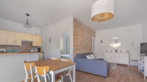 A modern kitchen with wooden cabinets, a dining table with chairs, a grey sofa, and a TV stand. - Appartement 3 Pièces Avec Terrasse au Calme Hyper Centre Arcachon - Mer à 50 m (Arcachon)