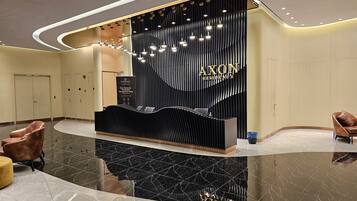 A modern reception desk with a black and gold design, a marble floor, and a curved ceiling with recessed lighting.