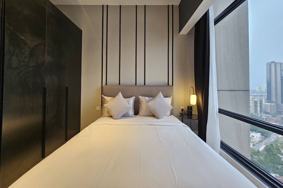 A modern hotel room with a large bed, a city view, and a minimalist design.