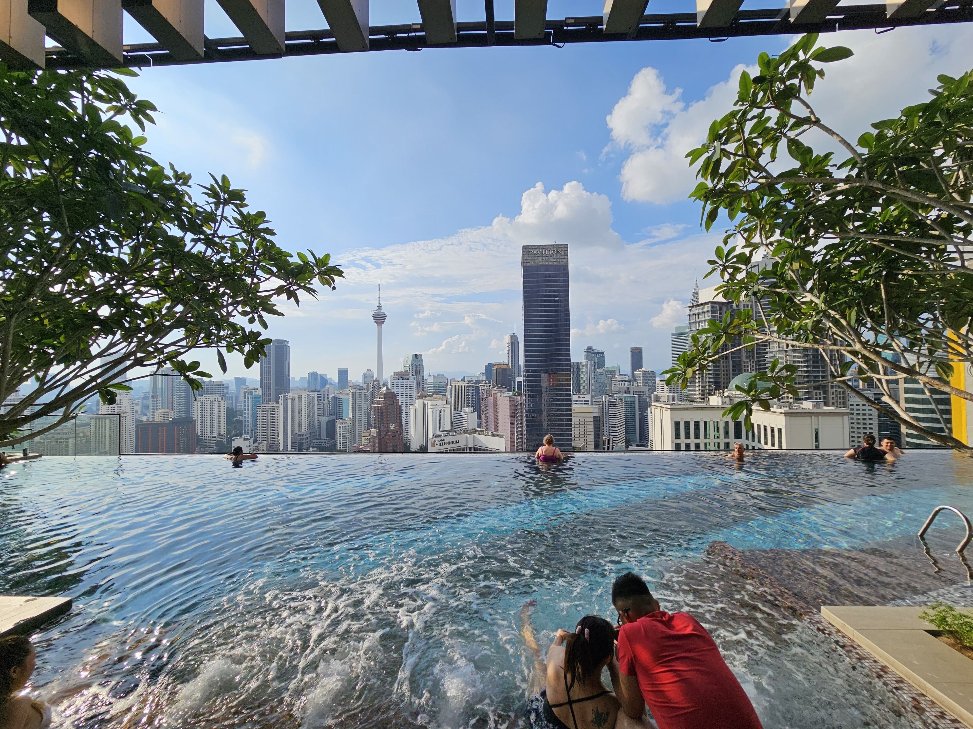 An infinity pool with a city skyline view, including a prominent tower.