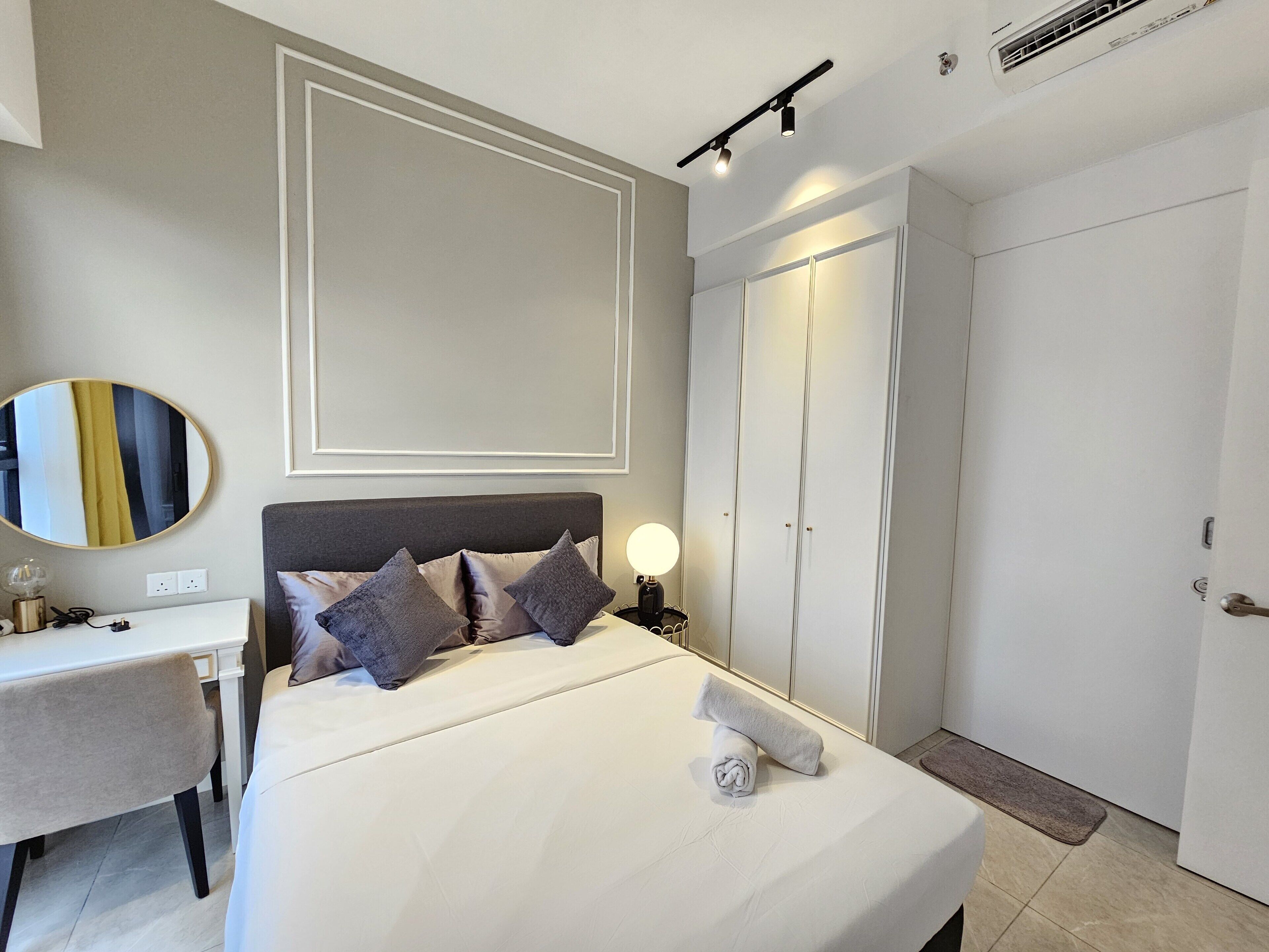 A hotel room with a bed, bedside table, lamp, and wardrobe.