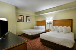 A hotel room with two beds, a TV, and artwork on the wall.