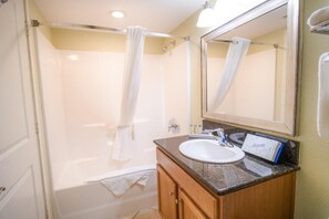 A bathroom with a shower, a sink, and a vanity.
