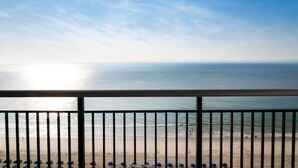 A beach view from a balcony with a railing, clear sky, and calm sea. - Coastal Retreat 3BRCondo with Full Amenities (Myrtle Beach)