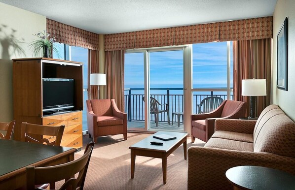 A hotel room with a balcony, a television, a dining table, and two sofas. - Beach Lover's Haven with Ocean-View Balconies (Myrtle Beach)