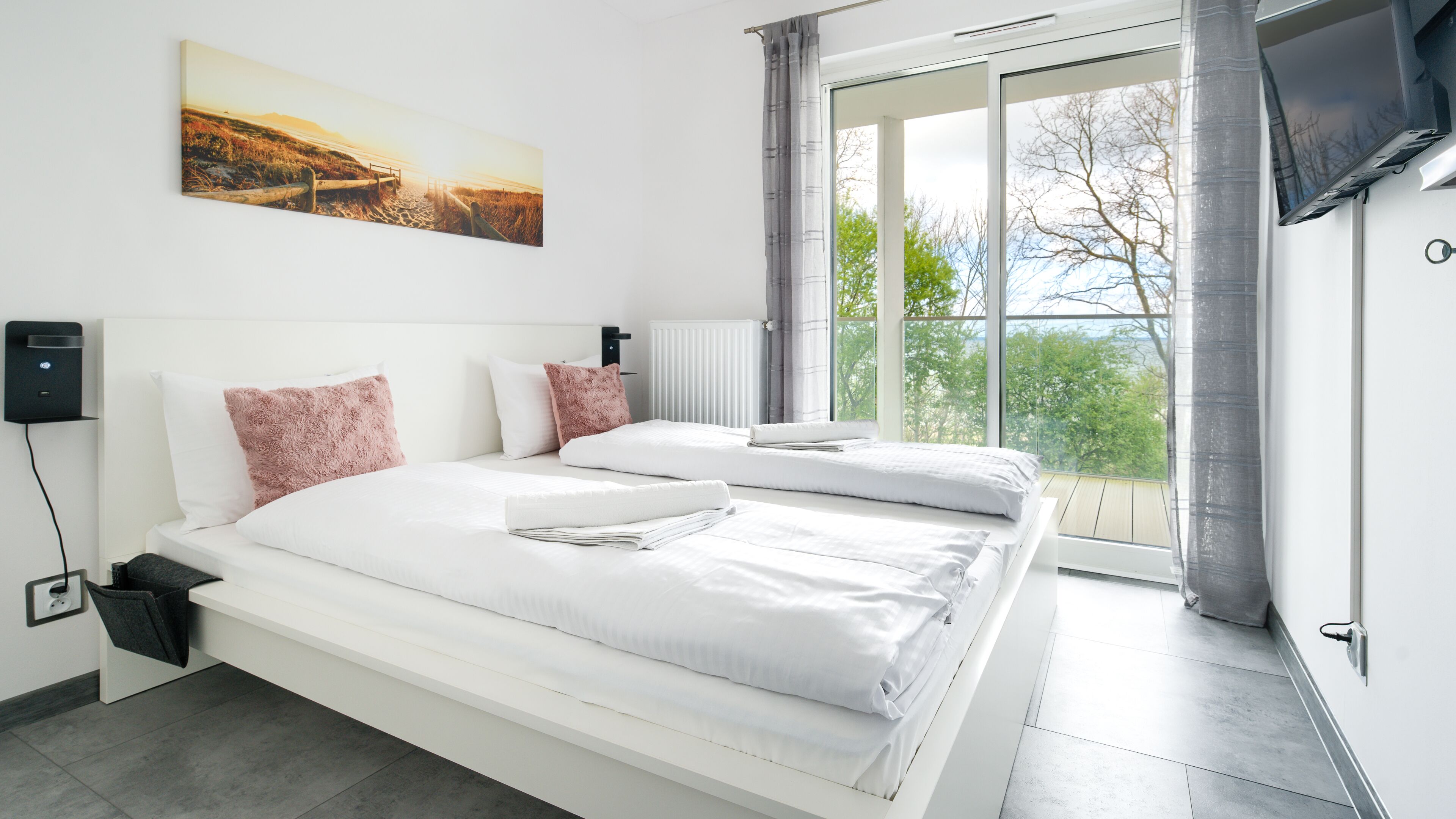 Ein modernes Schlafzimmer mit zwei Betten, einem großen Fenster und einem Gemälde an der Wand.