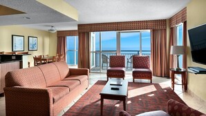 A hotel room with a balcony, a sofa, armchairs, a TV, and a dining area. - Penthouse Elegance on the Boardwalk 4 Bdrm 4 Bath (Myrtle Beach)